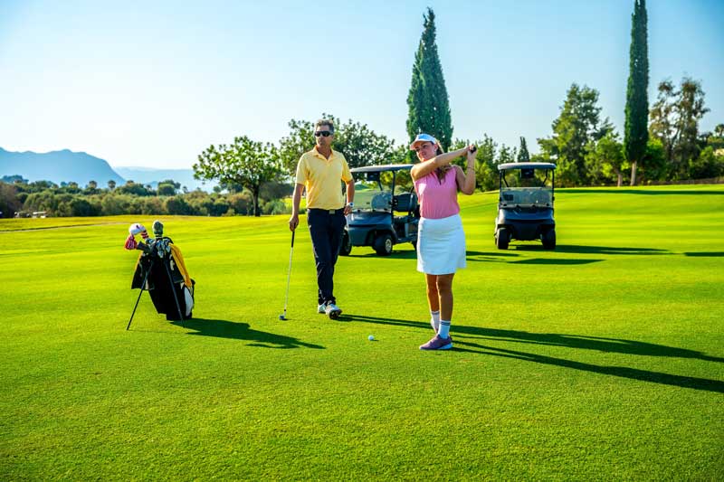 golf course construction financing - Photo description: Couple enjoying a sunny day on the golf course, playing together and relishing their leisure time in the vibrant outdoor setting