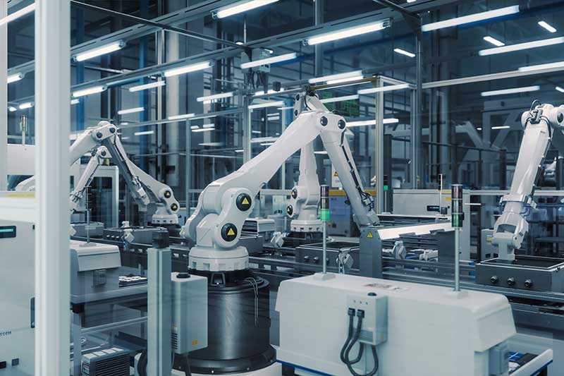 industrial and manufacturing financing company - photo of Tech Factory with White Robotic Arms Assembling Electronic Components on a Production Line Conveyor Belt.