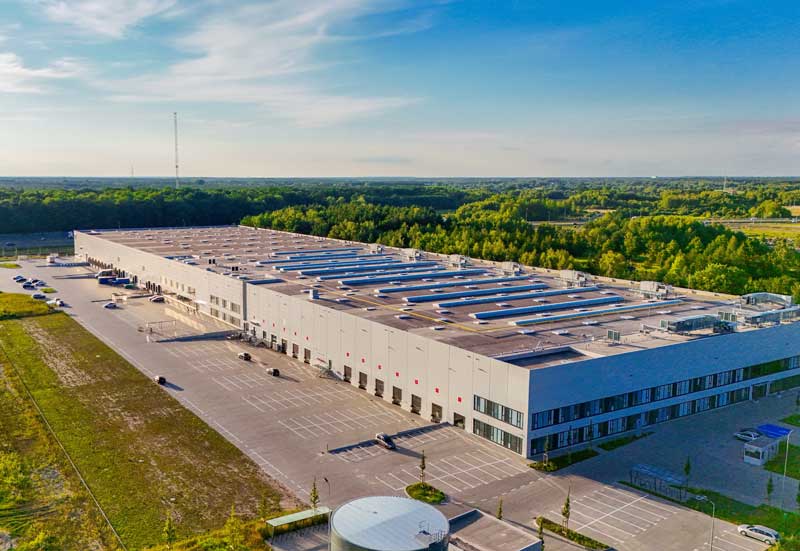 manufacturing business investment financing - aerial photo of a A modern warehouse with trucks, unloading and loading from ramps.