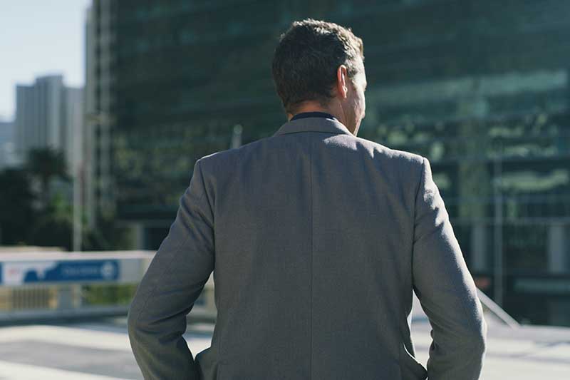 real estate equity financing - photo of a business man in a suit, photographed from behind, surveying a location, as a real estate developer might in an aspirational photograph.
