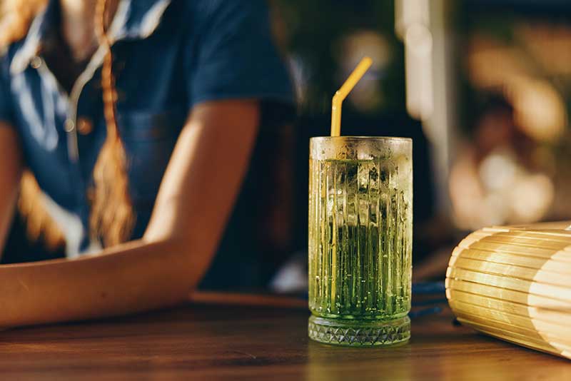 restaurant construction financing - photo description: Lifestyle woman in modern boho-western denim street style with a refreshing drink on the bar in warm film color lighting, casual and relaxed vibe.